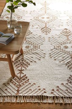 a table with a vase on top of it next to a white and brown rug