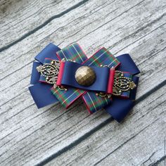 a blue and red bow with a gold button on it's side sitting on a wooden surface