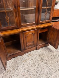 an old wooden china cabinet with glass doors on the top and bottom, sitting on a floor