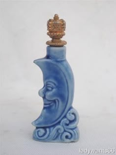 a blue bottle with a gold top sitting on a white table next to a crown