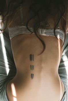 the back of a woman's body with tattoos on her lower and upper ribs