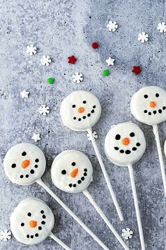 snowman cake pops with white frosting and colored candies on a gray surface