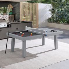 a pool table and two benches in a room with an outdoor kitchen area behind it