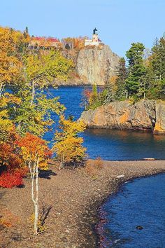 a lake surrounded by trees with a light house in the background