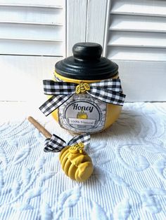 a jar of honey sitting on top of a table next to a wooden spoon with a ribbon around it