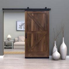 a living room with two vases on the floor and a barn door in the middle