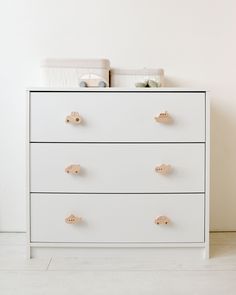 a white dresser with wooden handles and knobs on it's drawers in a room