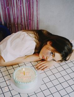 a woman laying on the floor next to a birthday cake with candles in her hand