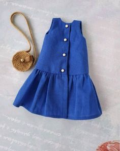 a blue dress with buttons and a straw bag