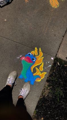 someone is standing on the sidewalk with their feet in front of chalk art that looks like a dragon