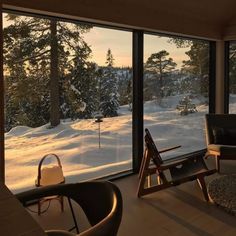 a living room filled with furniture next to a large window covered in snow and trees