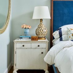 a bedroom with a blue headboard, white bedding and a mirror on the wall