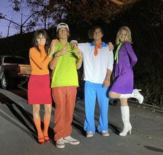 four people dressed up in costumes posing for a photo on the side of the road