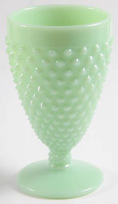 a green glass vase sitting on top of a white table