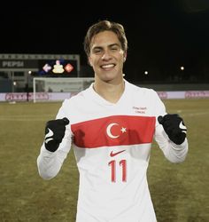 a soccer player is smiling and holding his hands in the air while standing on a field