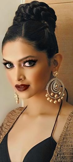 a woman with dark makeup and large earrings on her head, posing for the camera