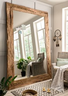 a large mirror sitting on top of a wooden floor next to a chair and table