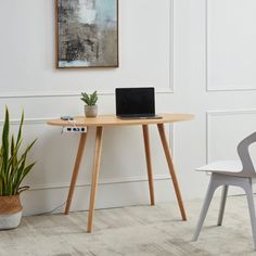 a laptop computer sitting on top of a wooden table next to a potted plant