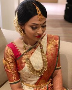 a woman sitting on top of a couch wearing a white and red sari with gold jewelry