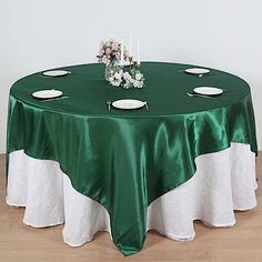 a green table with white plates and flowers on the top is sitting in front of a wall