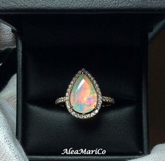 an opal and diamond ring in a black box