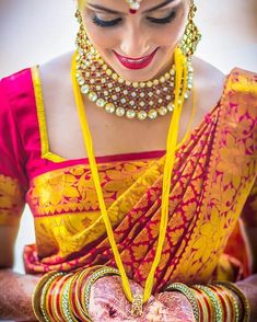 a woman in a yellow and red sari holding a heart shaped object with her hands