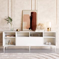 a living room with a white entertainment center and art on the wall, along with an area rug