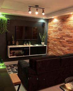 a living room with brick walls and plants on the wall, along with a black couch