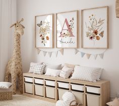 a room with three pictures hanging on the wall and two stuffed giraffes