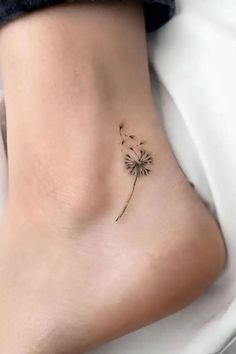 a small dandelion tattoo on the side of a woman's foot,