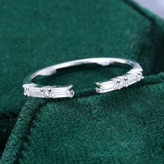 a white gold ring with three baguettes on it sitting on a green cloth