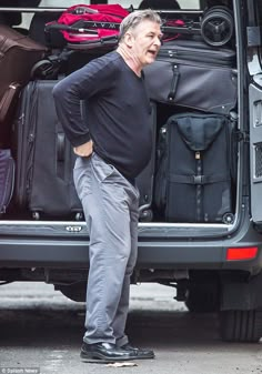 a man standing in front of a van filled with luggage