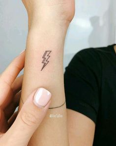 a woman's arm with a small lightning tattoo on the left side of her wrist