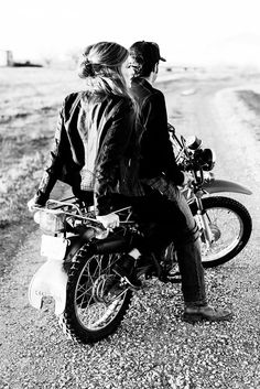 black and white photograph of two people sitting on a motorbike in the desert