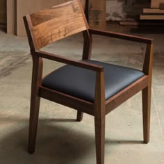 a wooden chair with black leather upholstered seat and backrest in a warehouse