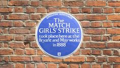 a blue plaque on a brick wall that says the match girls strike cook place here at the byzant and may works