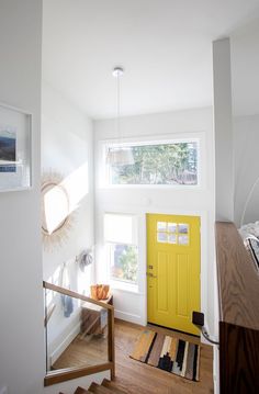 a bright yellow door sits in the corner of a white room next to a staircase