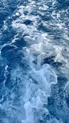 the back end of a boat traveling through the blue ocean with white foamy water