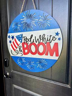 a red white and boom sign hanging on a door with fireworks in the sky behind it