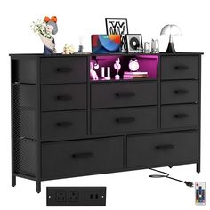 a black dresser with many drawers and pictures on it's top shelf next to a remote control