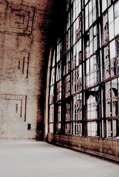 an old building with lots of windows on the wall and concrete flooring in front of it