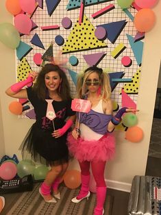 two women dressed up in costumes posing for the camera with balloons and confetti