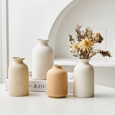 three white vases sitting on top of a table