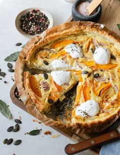 a quiche with cheese and other toppings sits on a cutting board next to some spices