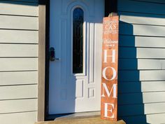 a wooden sign sitting in front of a door on the side of a house that says home