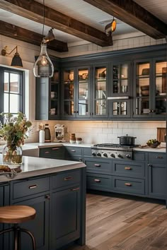 a large kitchen with blue cabinets and wooden floors is pictured in this image, there are two stools at the center of the island