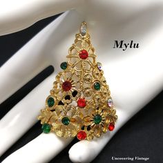 "*Description: This is a great Christmas tree brooch by Mylu from the 1960s. This brooch is featured in several of the vintage jewelry books including Coro Jewelry, A Collector's Guide by Marcia Sparkles Brown on page 230. She describes this brooch as \"gold plated flowers form a tree with rhinestone ornaments\". This brooch is featured in Christmas Tree Pins O Christmas Tree by Nancy Yunker Trowbridge on page 114. It is described as a lacy, floral design with an ornate scrolled base. The colore Gold Christmas Brooches For Festive Occasion, Christmas Tree Broach Brooch Pin, Mid-century Gold Brooches For Vintage Events, Gold Christmas Holiday Brooch, Rhinestone Ornaments, Coro Jewelry, O Christmas Tree, Vintage Swarovski Christmas Tree Brooch, Rhinestone Designs