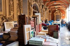 there are many books on the table in this room with people walking by it and one person is looking at them