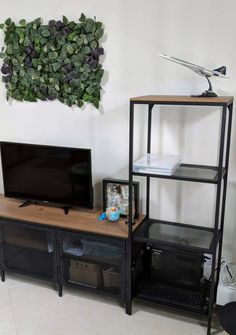 a flat screen tv sitting on top of a wooden stand next to a black shelf