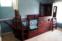 a wooden bed with drawers underneath it and a ladder to the top of it, in a room with blue walls